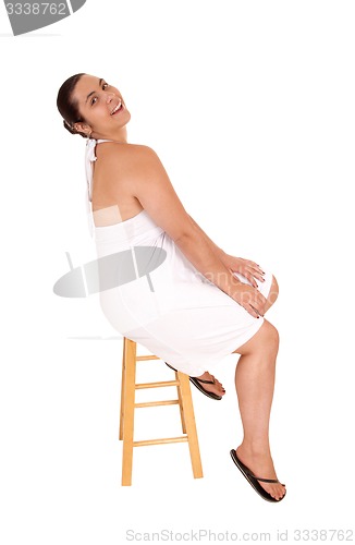 Image of Woman in white dress sitting on chair.