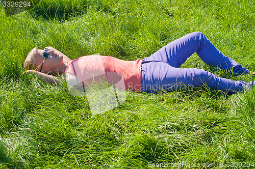 Image of Young man in orange lying on the green grass