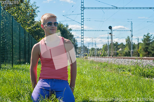 Image of Young man in orange sitting on the green grass