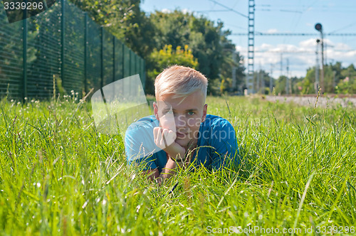 Image of Young man in blue t-shirt lying on the green grass