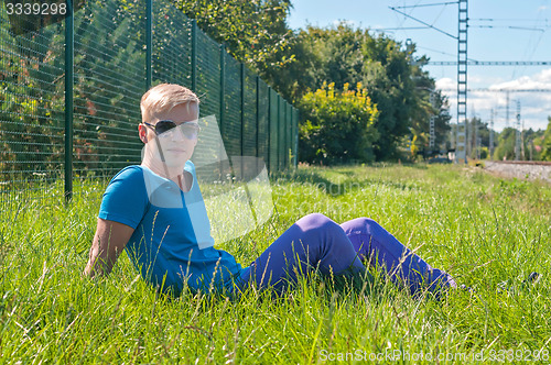 Image of Young stylish man lying on the green grass