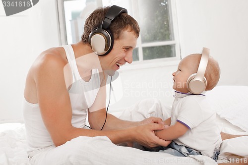 Image of young father with his nine months old som on the bed at home