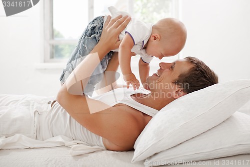 Image of young father with his nine months old som on the bed at home