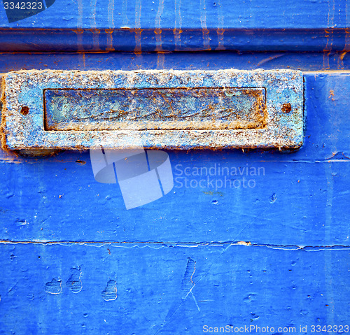 Image of dirty stripped paint in the blue wood door and rusty nail