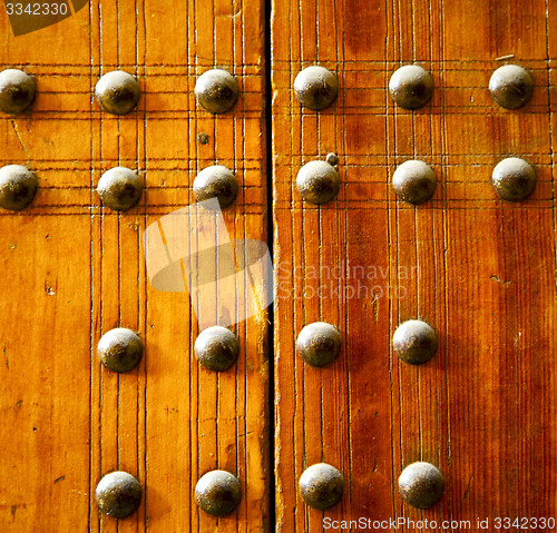 Image of metal nail dirty stripped paint in the brown   red wood door and