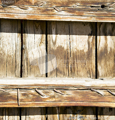 Image of nail dirty stripped paint in the brown wood door and rusty yello