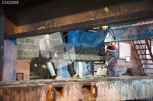 Image of Workers operates machine with trowels