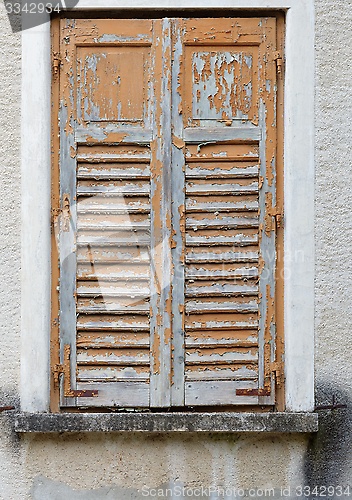 Image of Closed window of the old building covered by wooden blinds with peeling paint