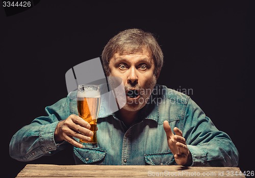 Image of The enchanted and emotional fan with glass of beer