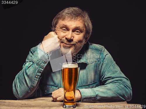 Image of The satisfied man in denim shirt with glass of beer