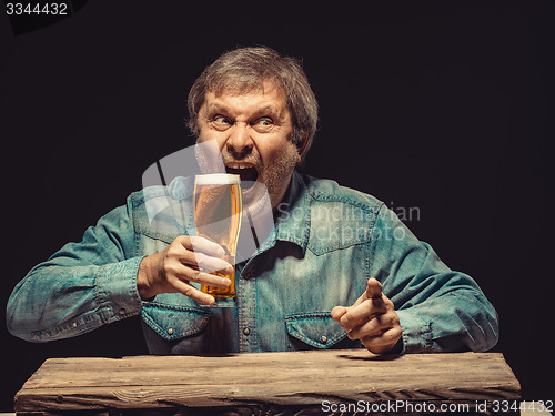 Image of The screaming man in denim shirt with glass of beer