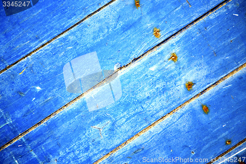 Image of dirty stripped    e blue wood door and rusty nail