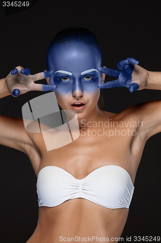 Image of Portrait of a woman who is posing covered with blue paint