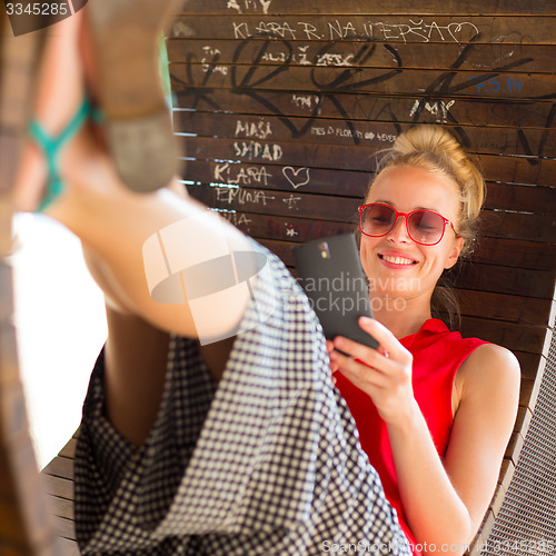 Image of Young cheerful woman using smarthphone.