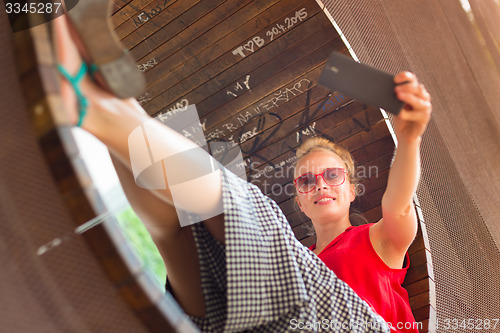 Image of Young cheerful lady taking selfie.