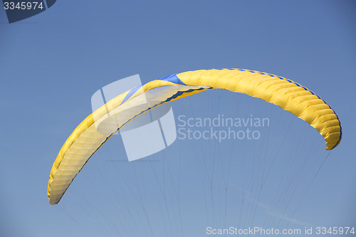 Image of Yellow paraglider with blue sky