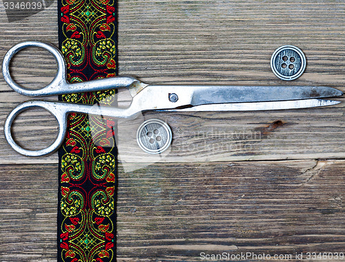 Image of embroidered tape, vintage buttons and a tailor scissors