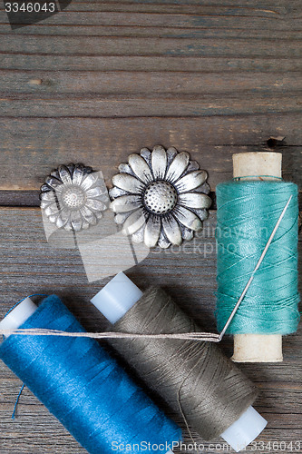 Image of two vintage buttons flowers and spools with threads