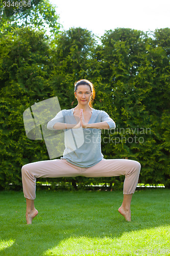 Image of adult woman doing yoga exercises in the park