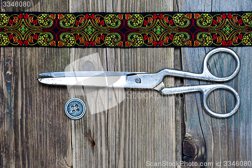 Image of vintage button, emroidered band and a tailor scissors
