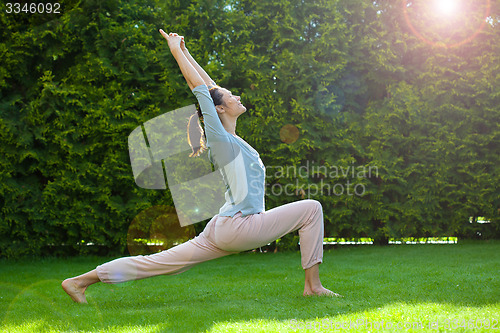 Image of pretty adult woman doing yoga on grass
