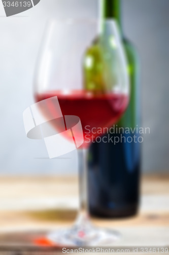 Image of red wine in glass and green bottle