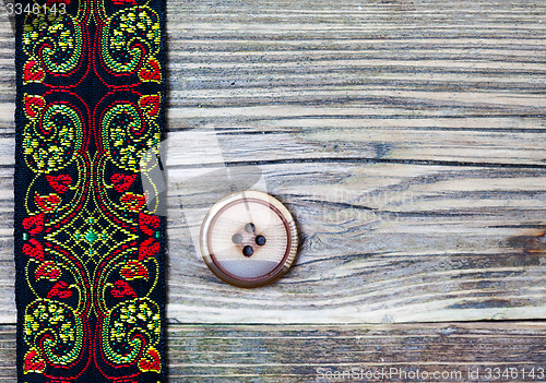 Image of old band with embroidered ornaments and vintage button