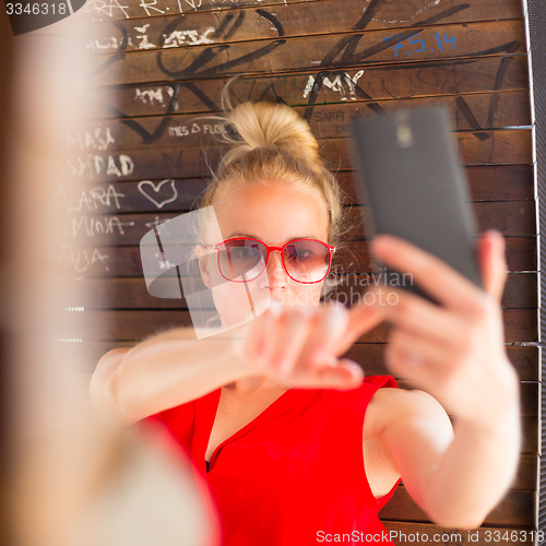 Image of Young cheerful lady taking selfie.