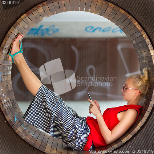 Image of Young cheerful woman using smarthphone.