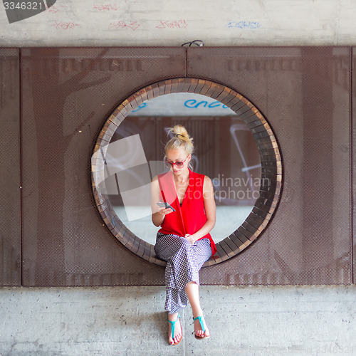 Image of Young cheerful woman using smarthphone.