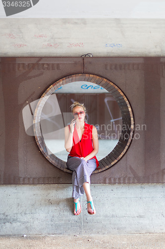 Image of Young cheerful woman talking on cellphone.