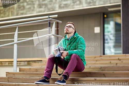 Image of young hipster man with digital camera in city