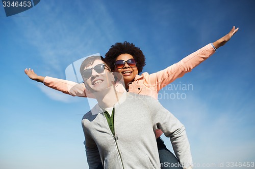 Image of happy teenage couple in shades having fun outdoors