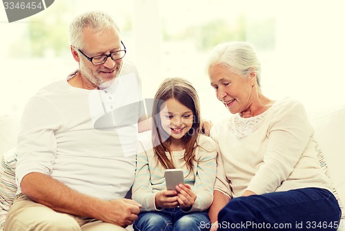 Image of smiling family with smartphone at home