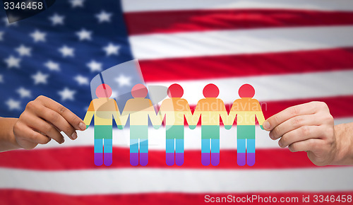 Image of hands holding rainbow people over american flag