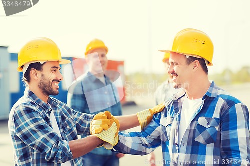 Image of group of smiling builders in hardhats outdoors