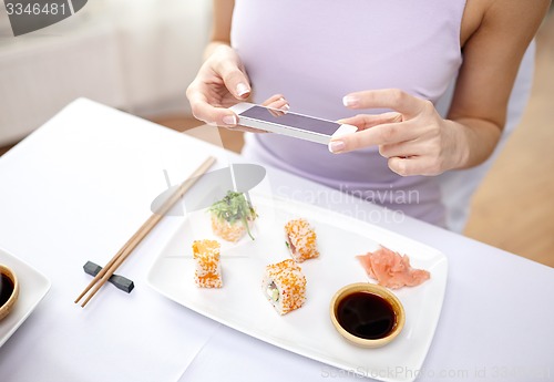 Image of woman with smartphone taking picture at restaurant