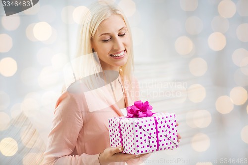 Image of smiling woman with gift box over holidays lights