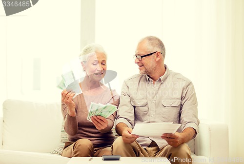 Image of senior couple with money and calculator at home