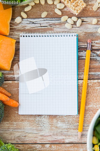 Image of close up of ripe vegetables and notebook on table