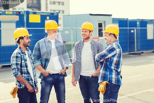 Image of group of smiling builders in hardhats outdoors