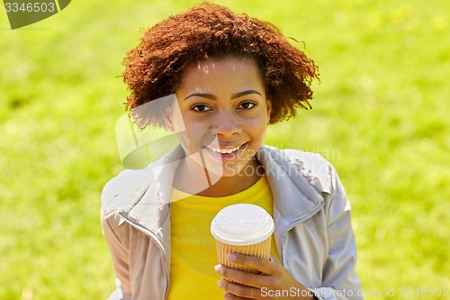 Image of smiling african woman drinking coffee outdoors 