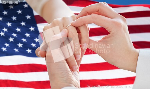 Image of close up of lesbian couple hands with wedding ring