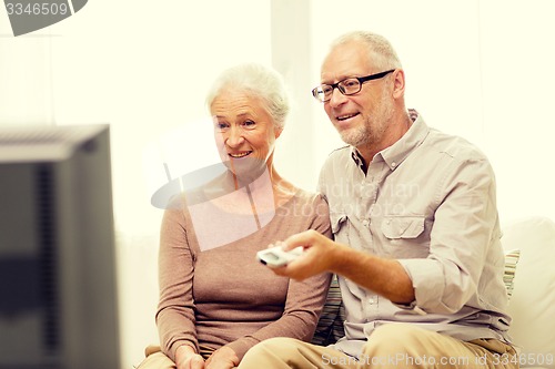 Image of happy senior couple watching tv at home