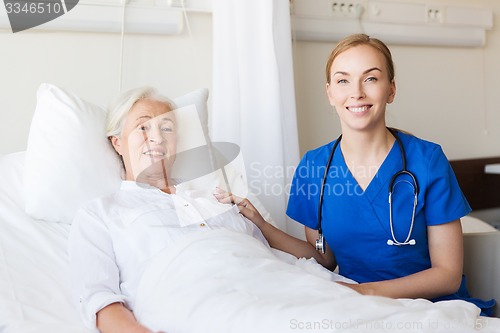 Image of doctor or nurse visiting senior woman at hospital