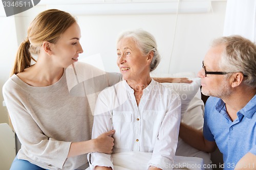 Image of happy family visiting senior woman at hospital