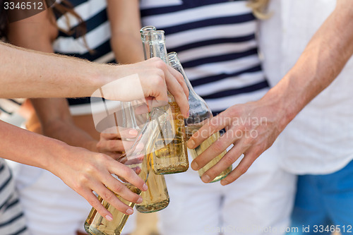 Image of close up of hands clinking bottles with drinks