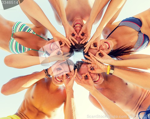 Image of smiling friends in circle on summer beach