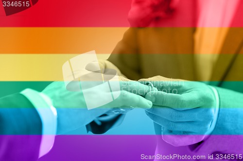 Image of close up of male gay couple hands and wedding ring