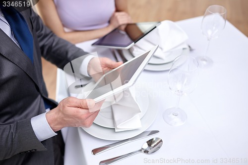 Image of close up of couple with tablet pc at restaurant